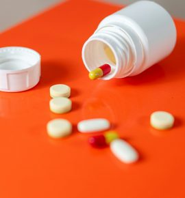 spilled-pill-bottle-with-various-medications-on-orange-surface.jpg